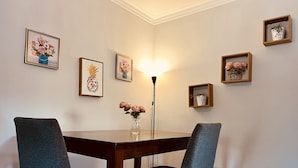 A dining area with a wooden table and two chairs, a vase with flowers, and several framed artworks on the wall. - acogedor apartamento acceso directo al jardín en primera linea zona con segurida (La Guáyiga)