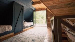 Ein Schlafzimmer mit einem Bett, einem hölzernen Deckenventilator und einem großen Fenster.