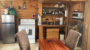 A compact kitchen with a refrigerator, stove, microwave, and a dining area with two chairs and a table. - Couple get away retreat in Red Feather Lakes!! (Red Feather Lakes)