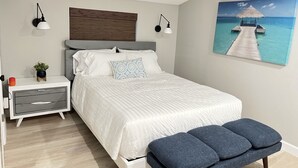 Una camera da letto con un letto, comodini, una panca, un quadro e una testiera in legno.
