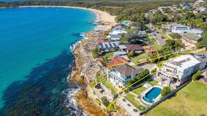 Vista aérea de una zona residencial costera con casas, una playa y un acantilado sobre el océano.