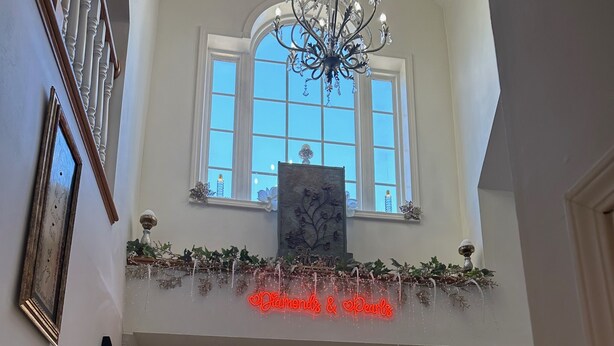 Ein prachtvoller Eingangsbereich mit einem Chandelier, einem dekorativen Schild und einer Tür mit Buntglasfenstern.