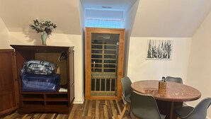 Ein kleines Zimmer mit einem Holzschrank, einem Tisch mit Stühlen und Holzboden.