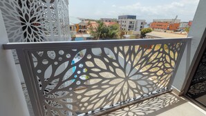 A balcony with a decorative metal railing and a view of buildings in the background. - D'Magnolia Luxury Apartments (Madina)