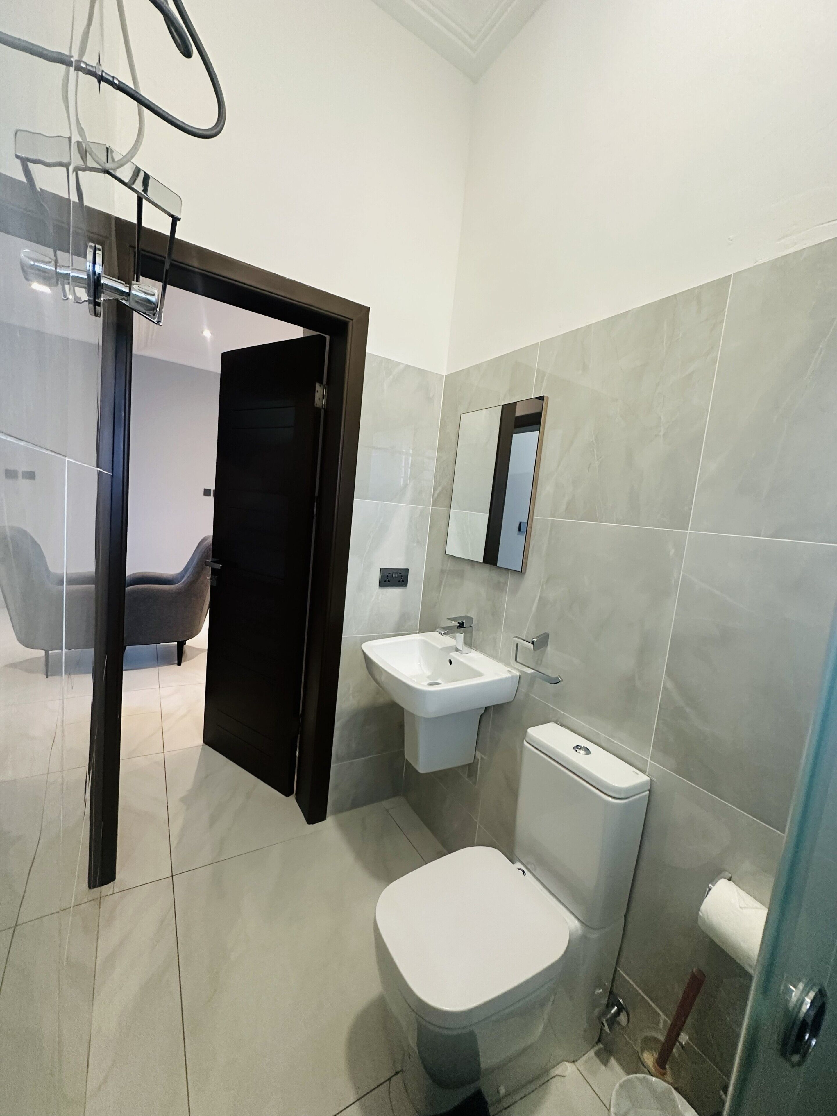 A modern bathroom with a toilet, sink, and mirror.