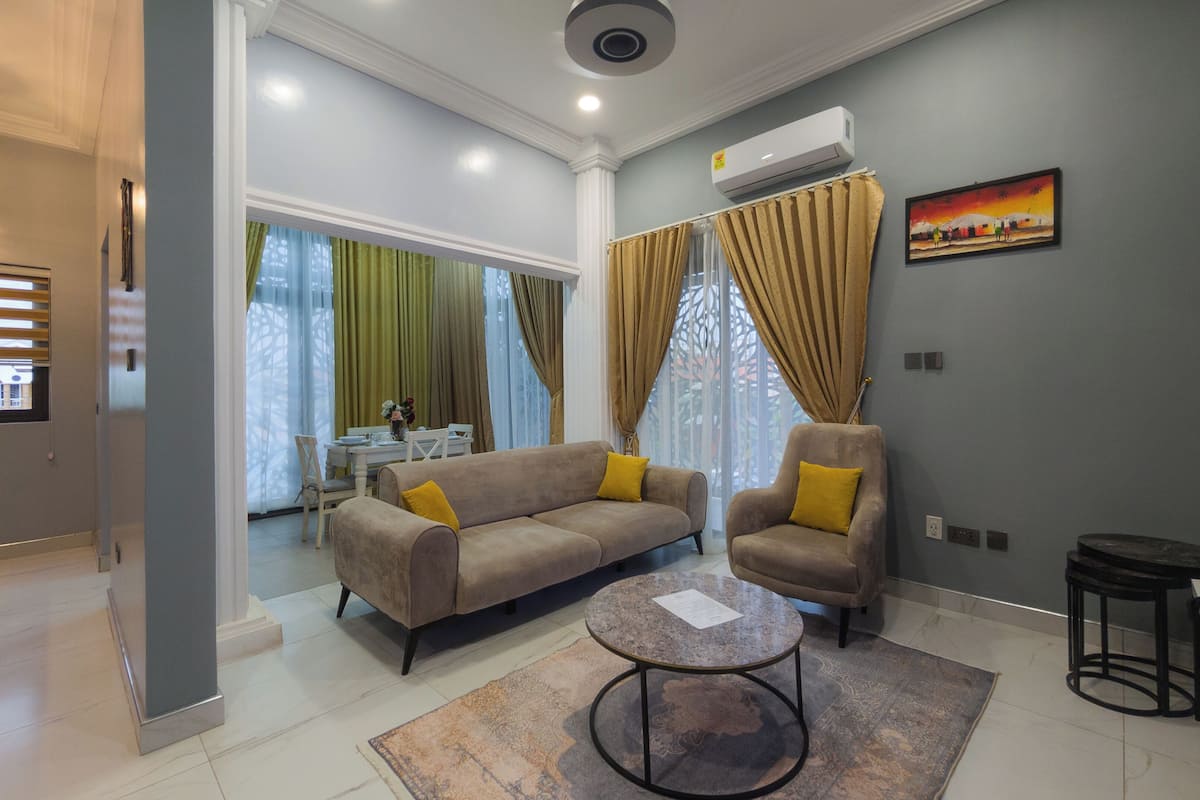 A modern living room with a sofa, armchairs, a coffee table, and a painting on the wall.