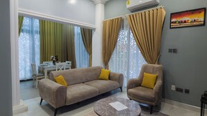 A living room with a sofa, armchair, coffee table, and a patterned rug. - D'Magnolia Luxury Apartments (Madina)