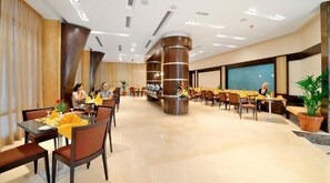 Experience the modern lobby with a central seating area, potted plants, and a large screen for presentations.