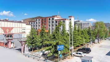 A hotel with a parking area, a sign indicating parking availability, and a view of the surrounding buildings and trees.