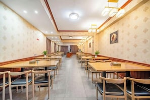 A hotel dining area with multiple tables and chairs, a reception desk, and patterned wallpaper. - Salong Hotel (Shangri-La)