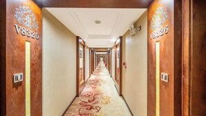 Een hotelgang met een tapijtvloer, houten wanden en kamer nummers V8325 en V8326 aan de linker- en rechterwand.