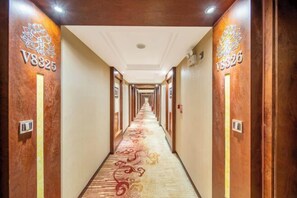 A hotel hallway with a carpeted floor, wooden walls, and room numbers V8325 and V8326 on the left and right walls, respectively.