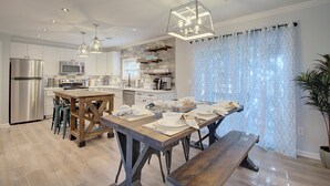 A modern kitchen with stainless steel appliances, wooden dining table, and pendant lighting. - Steps to Oak Island Beach | Private Pool | Pet Friendly | Beach Gear (Oak Island)