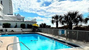 A swimming pool with a clear blue sky and palm trees in the background. - Ambassador #224 w/Amazing Beach Front View ~ Pool ~ Hot Tub ~ Pier Park~ Pets Ok (Panama City Beach)