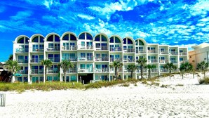 A beachfront hotel with multiple balconies, palm trees, and a sandy beach. - Ambassador #224 w/Amazing Beach Front View ~ Pool ~ Hot Tub ~ Pier Park~ Pets Ok (Panama City Beach)
