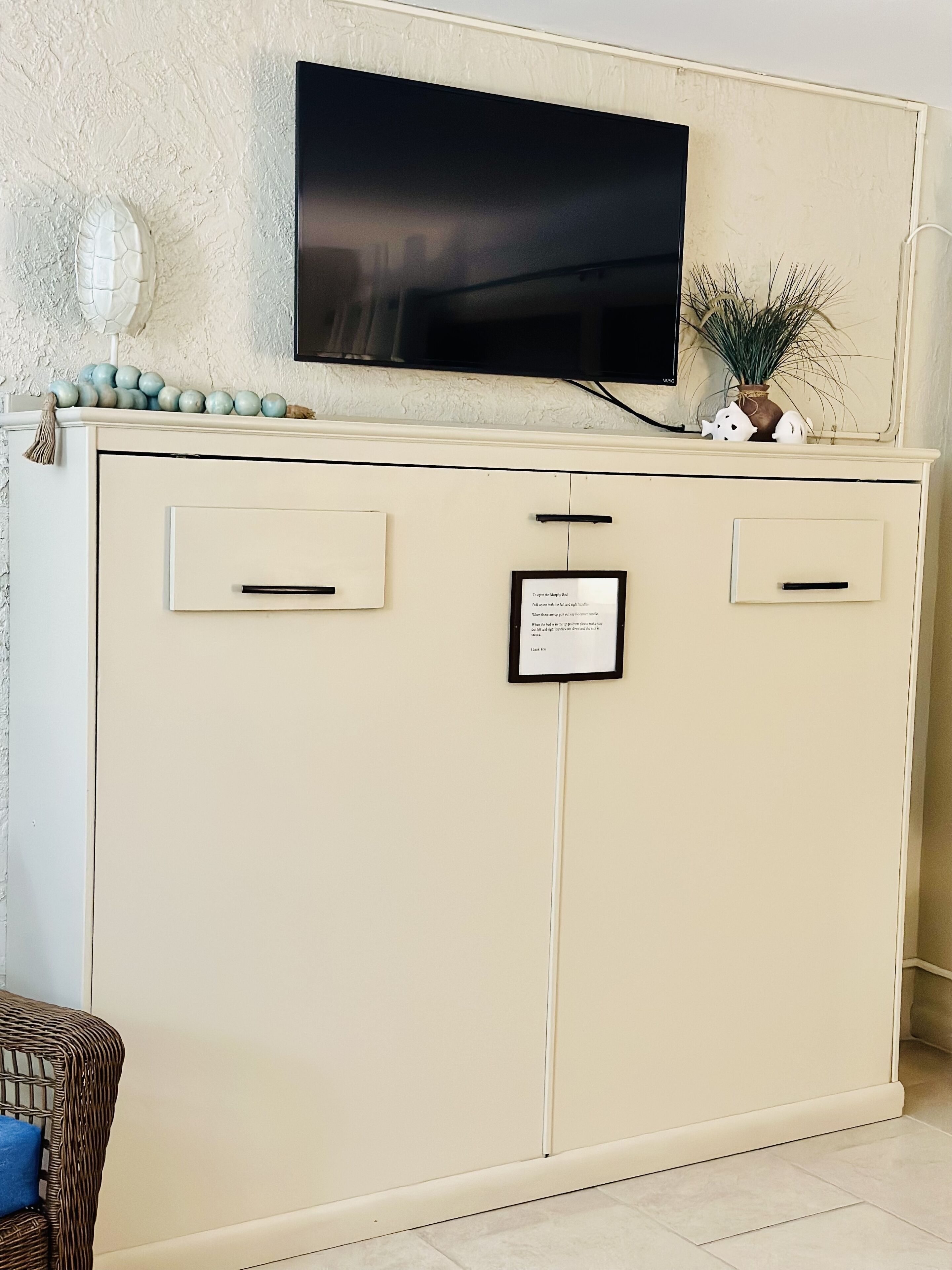 Un mueble color crema con dos cajones y un televisor montado encima.