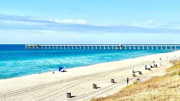 A beach with a pier extending into the ocean, a sandy path, and trash bins along the side. - Ambassador #224 w/Amazing Beach Front View ~ Pool ~ Hot Tub ~ Pier Park~ Pets Ok (Panama City Beach)