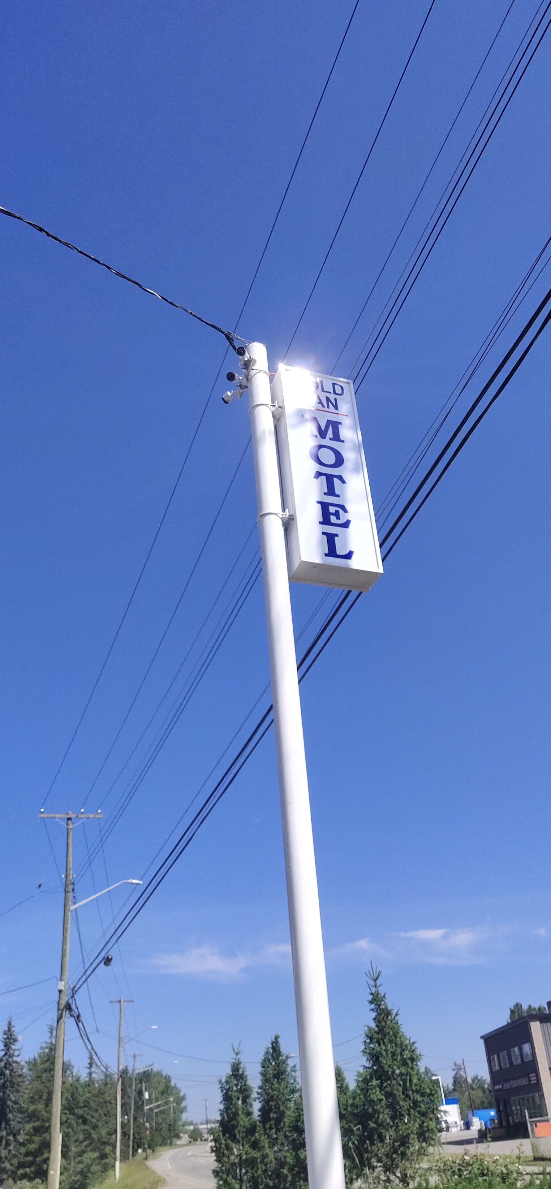 A motel sign on a pole with power lines in the background.