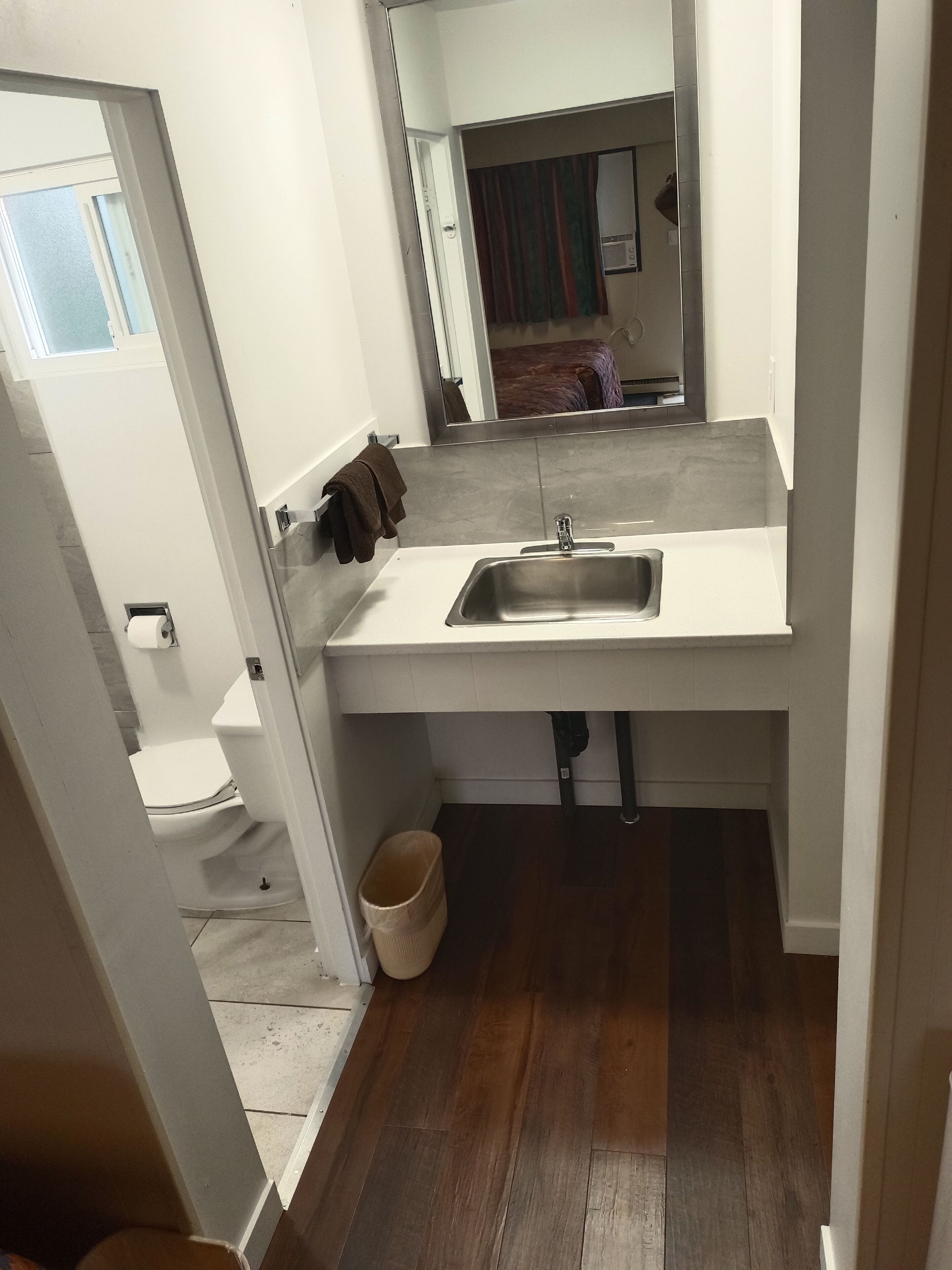 Une petite salle de bain avec un lavabo blanc, des toilettes et une petite poubelle.