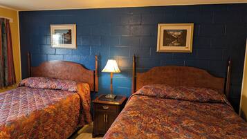 A room with two beds, a nightstand, a lamp, and two framed pictures on the wall.