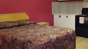 Ein Schlafzimmer mit einem Bett, einem Nachttisch, einem weißen Kleiderschrank und einem schwarzen Herd.