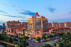 A multi-story hotel with a central tower, surrounded by other buildings, and a busy street in the foreground. - Kela Hotel (Fenyi)