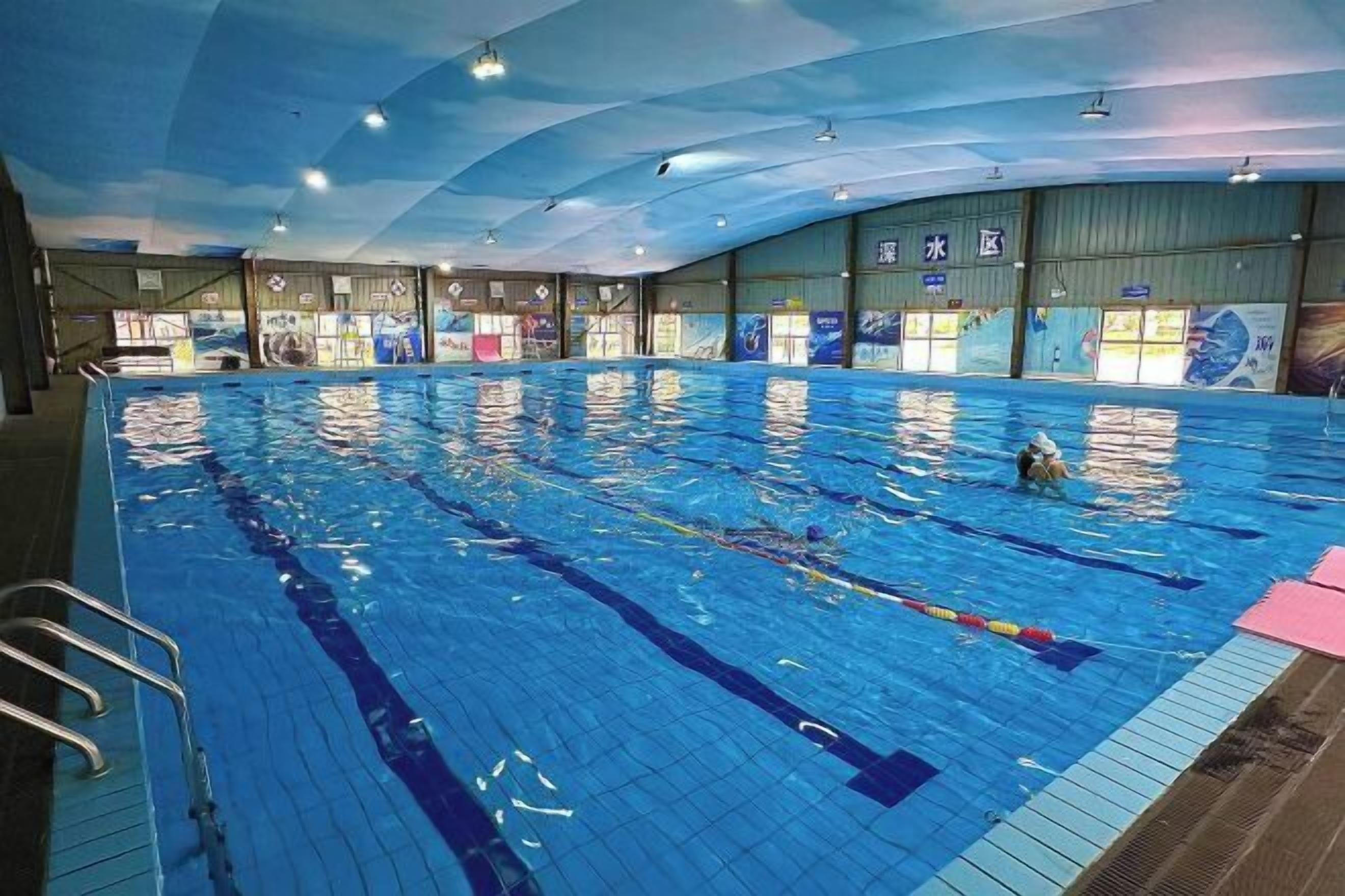 Piscina interior con carriles delimitados y socorrista.