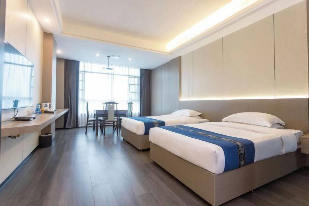 A hotel room with two beds, a desk, and a chair.