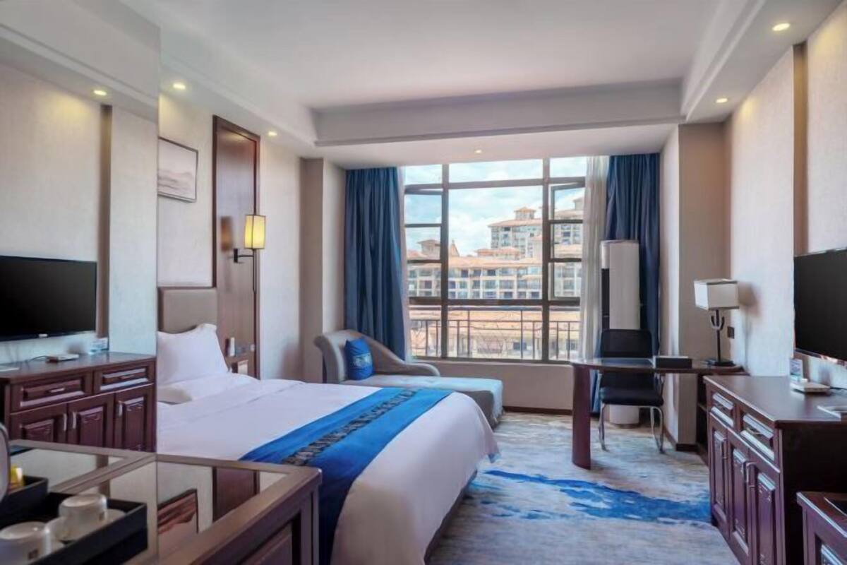 A hotel room with a large bed, a desk, a chair, and a TV.