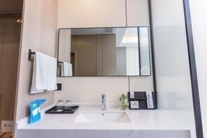 A modern bathroom with a white sink, a large mirror, and a towel rack. - Kela Hotel (Fenyi)