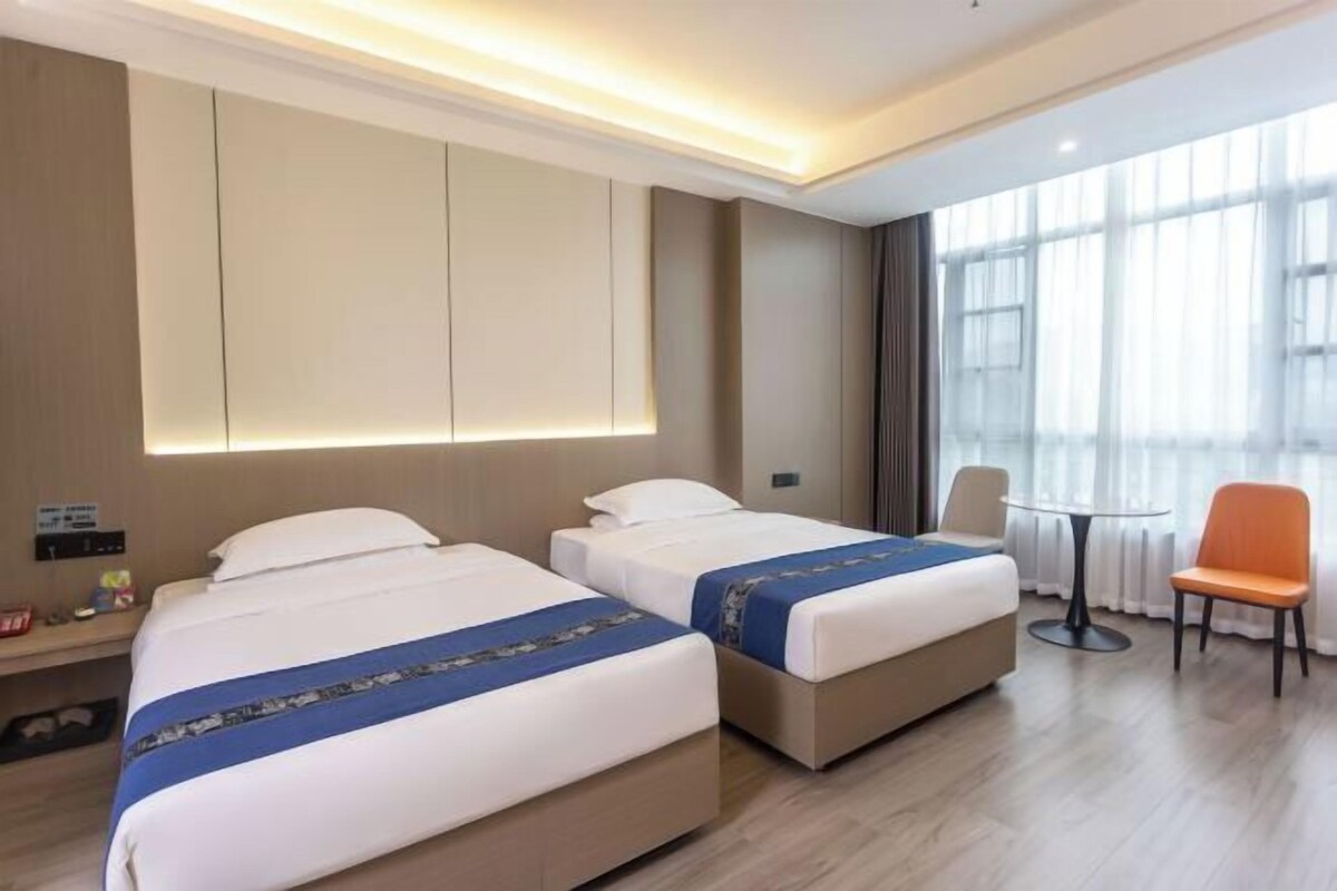 A hotel room with two beds, a small table, and a chair.