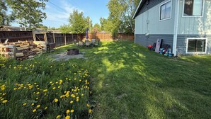 Ein Garten mit einer Holzterrasse, einer Feuerstelle und einem Schuppen.
