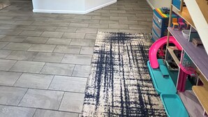 Ein geräumiger Raum mit hoher Decke, einem Spielbereich mit Spielzeug und einer Treppe.