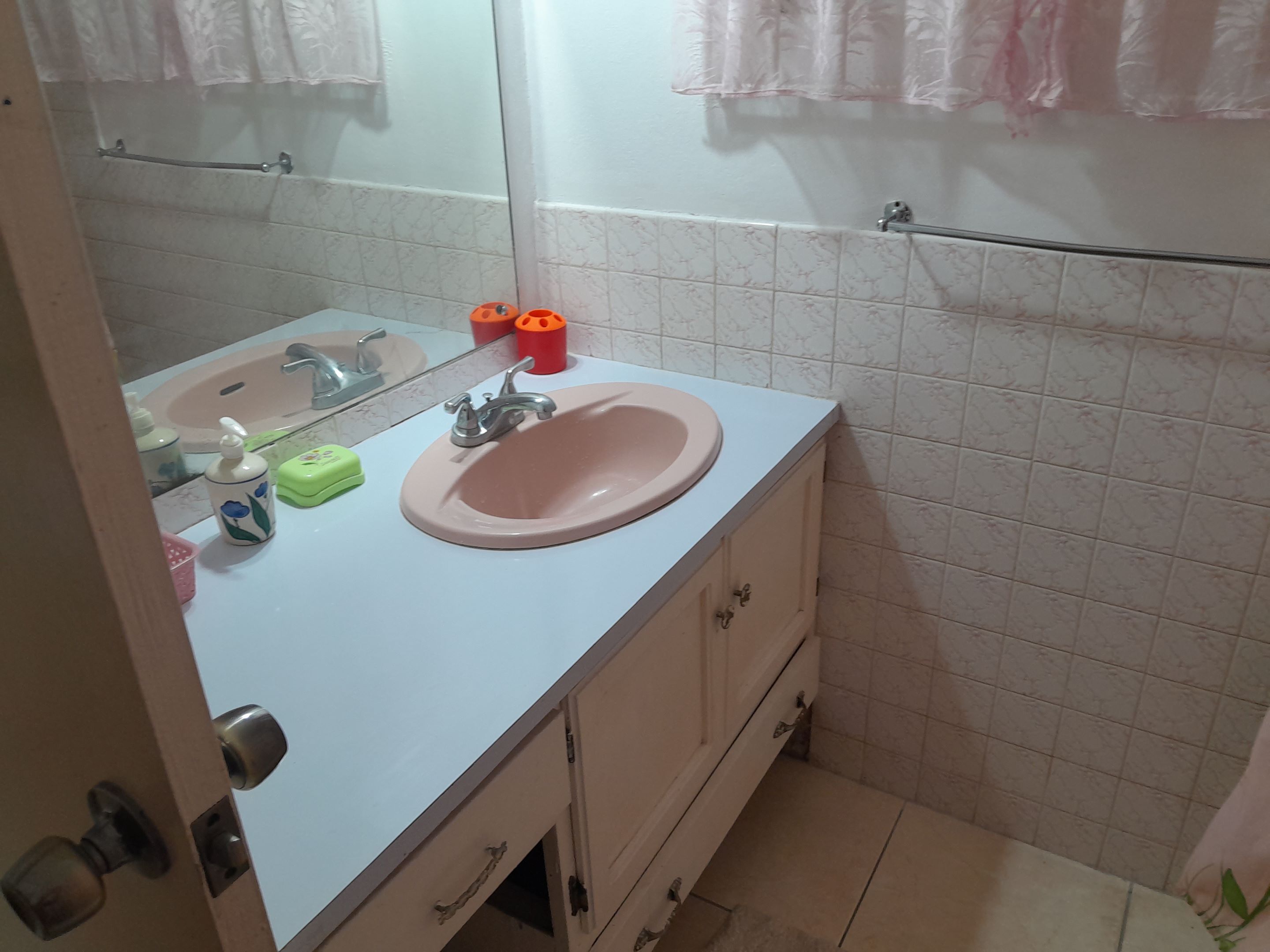 A bathroom with a white sink, a mirror, a towel rack, and a toilet.