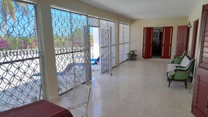A spacious balcony with metal railings, a covered table, and two green chairs. - Villa Chinnor (Montego Bay)