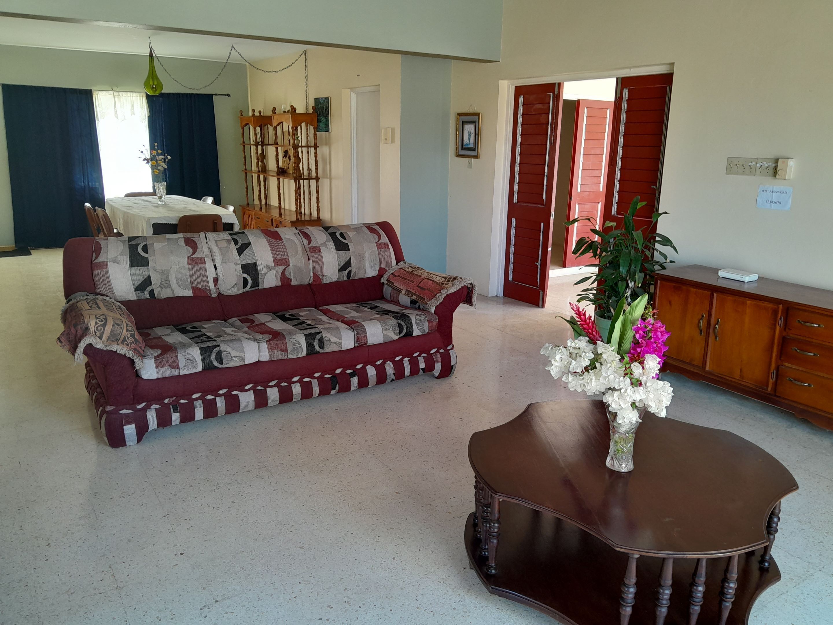 Una sala de estar con un sofá, una mesa de centro, un aparador de madera y una planta en maceta.