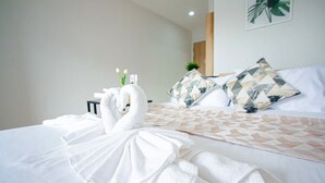 A hotel room with a neatly made bed, two swan-shaped towels, and a geometric-patterned bedspread. - ATC Residence (Bangkok)