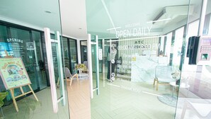 A modern interior with a reception desk, glass doors, and a sign indicating the business hours. - ATC Residence (Bangkok)
