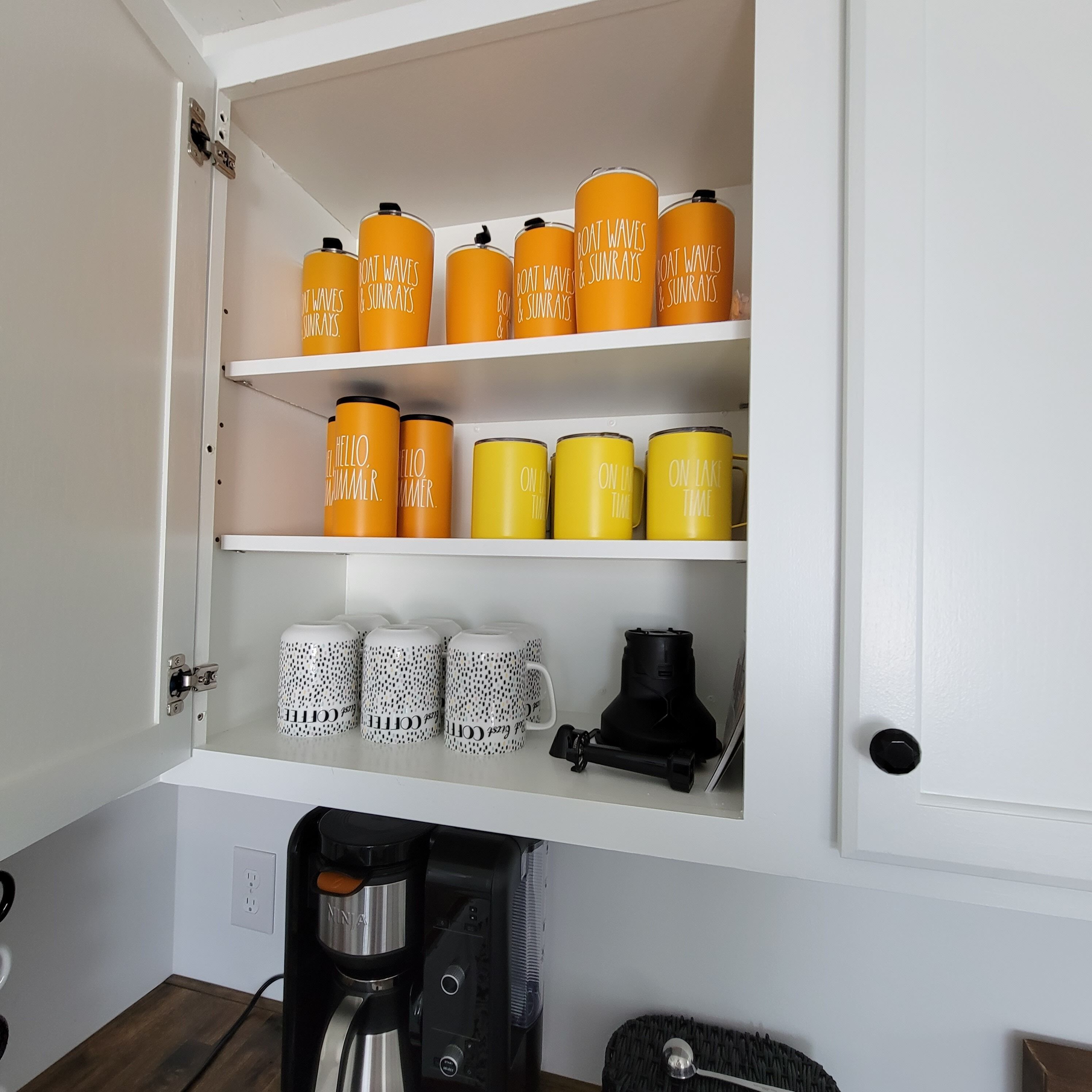 A kitchen cabinet with storage shelves holding various containers and a coffee maker.