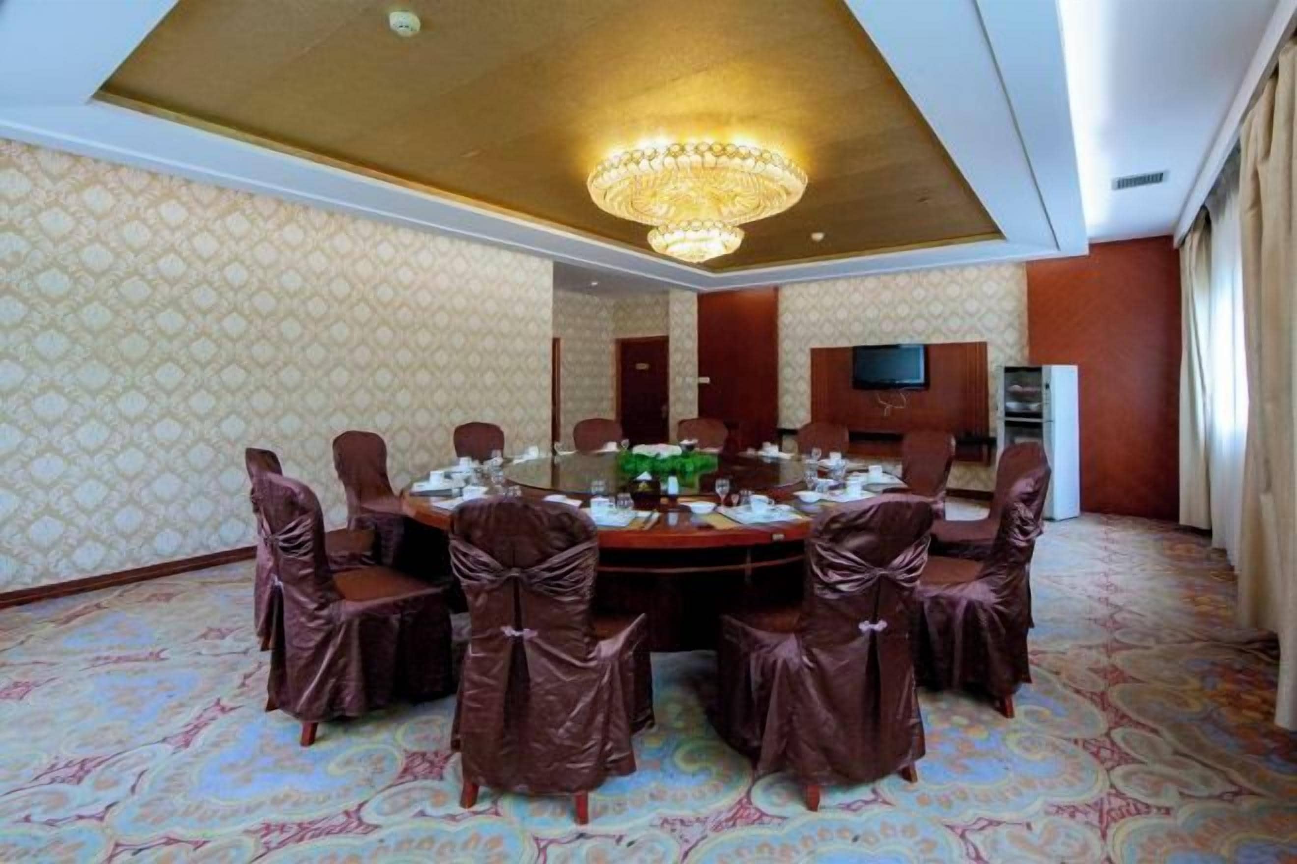 Uma sala de conferências com uma mesa redonda, cadeiras e um candelabro.