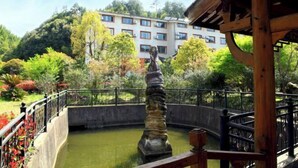 Un patio con una fuente, rodeado de vegetación y un edificio al fondo.