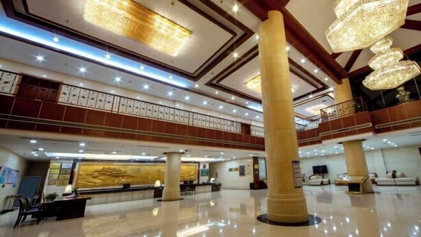 Un vestíbulo amplio con techos altos, grandes candelabros y un piso pulido.