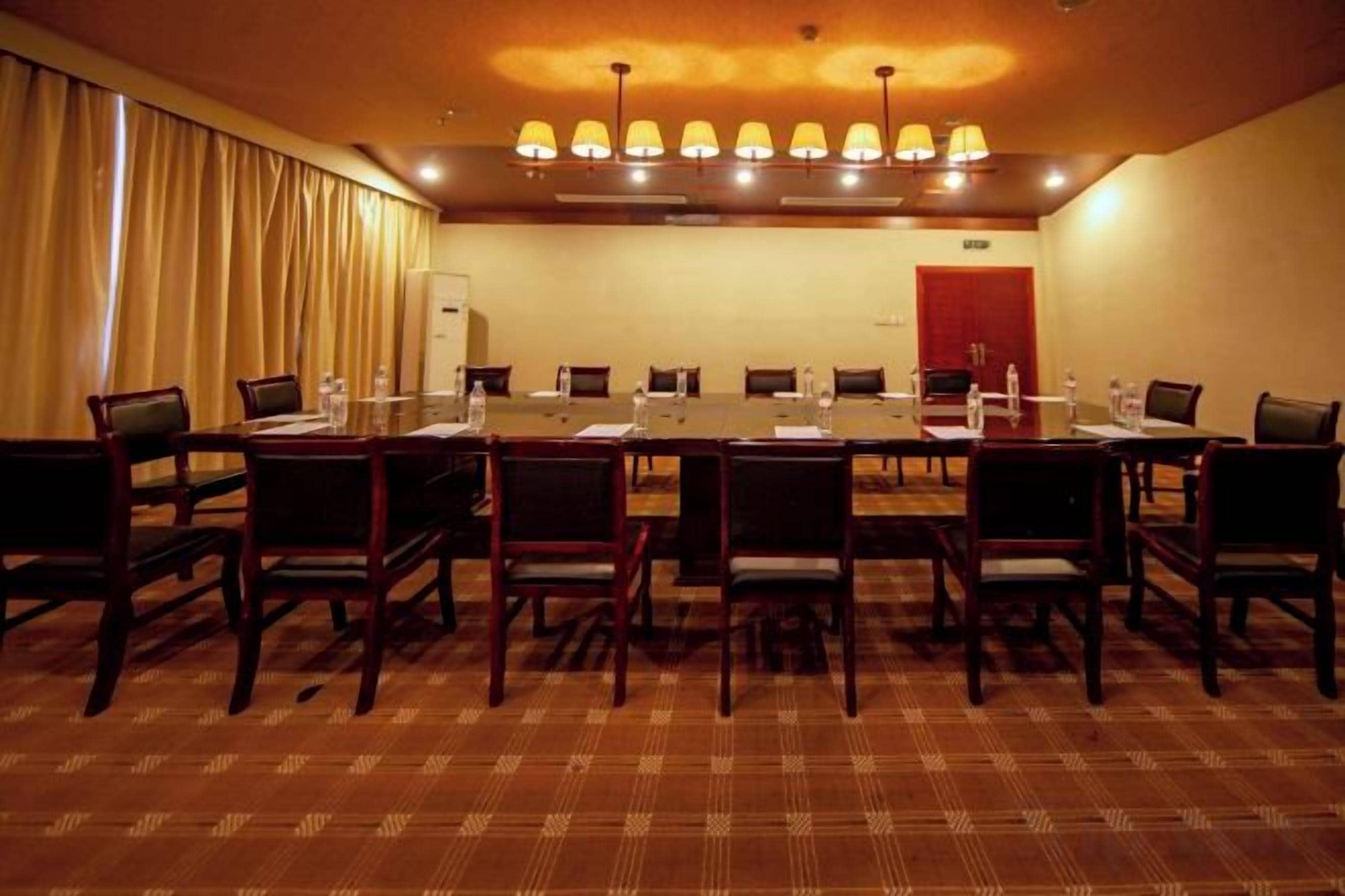 Una sala de conferencias con una larga mesa, sillas y una puerta roja al fondo.