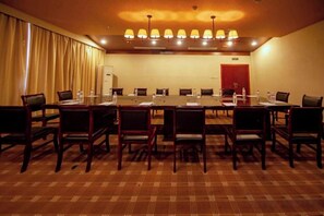 A conference room with a long table, chairs, and a red door in the background.