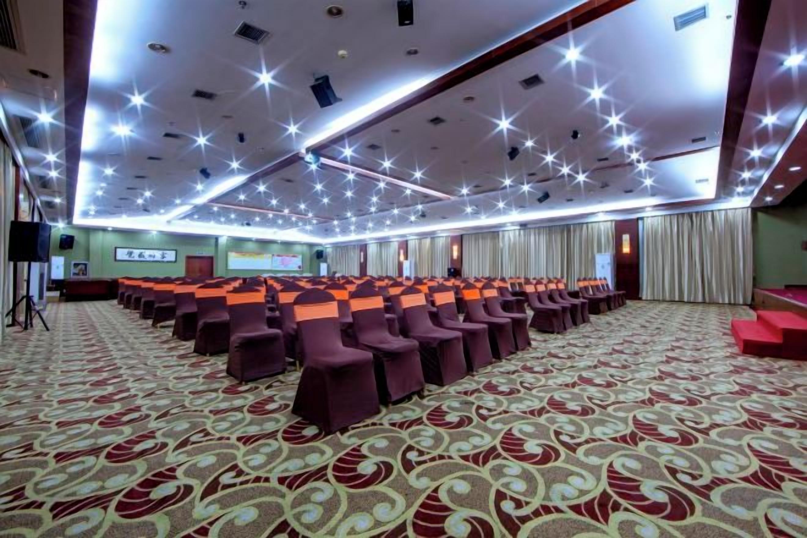 A conference room with rows of chairs, a carpeted floor, and a ceiling with star-like lights.