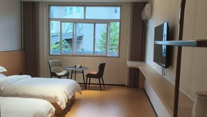Habitación de hotel con dos camas, televisión, una mesita y una silla.