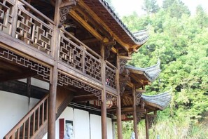 Une structure traditionnelle en bois, ornée de motifs complexes en treillis et dotée d’un toit  à plusieurs niveaux.