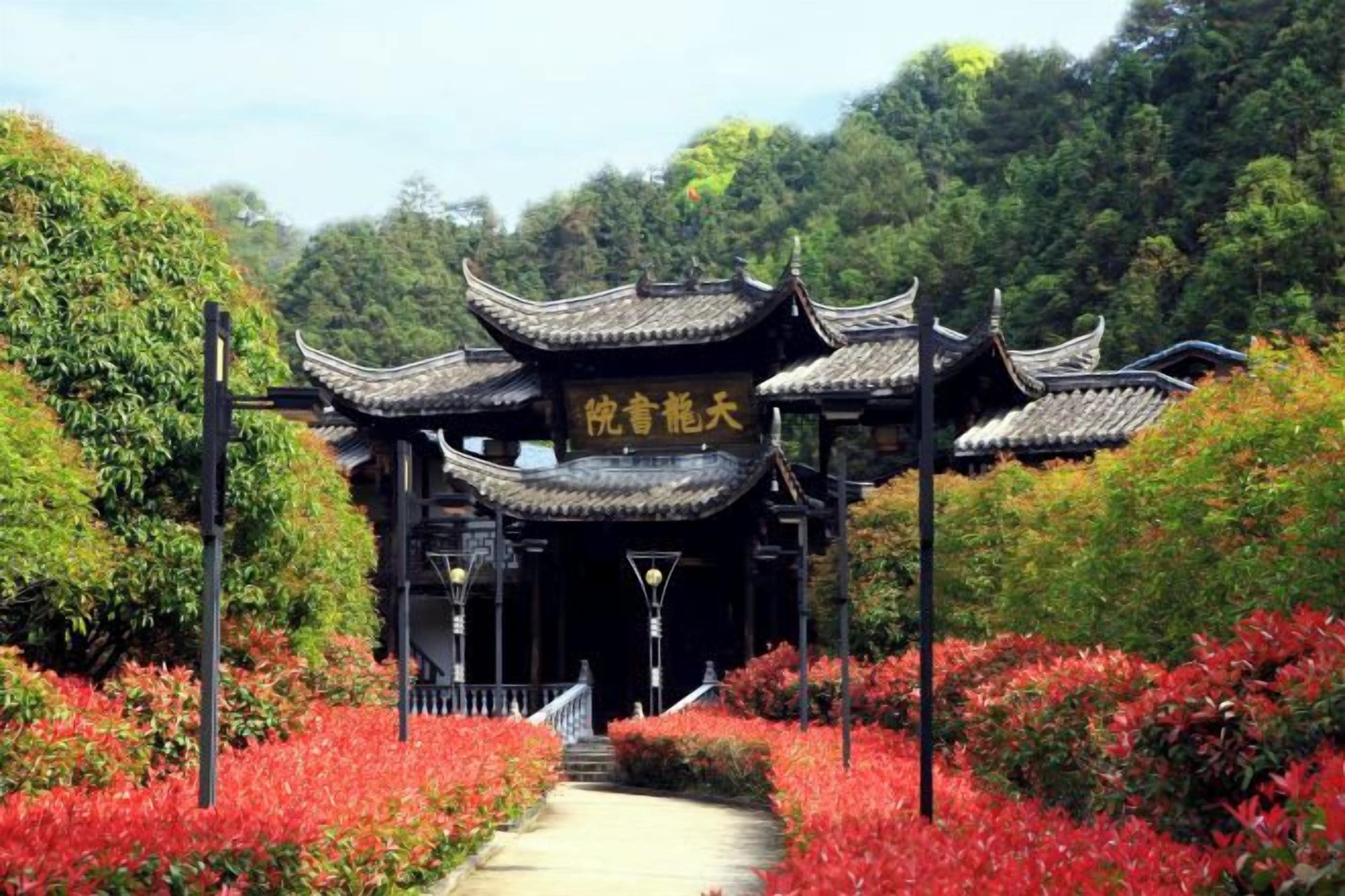 Ein traditionelles chinesisches Tor mit einem Weg, der durch einen Garten mit roten Blättern führt.
