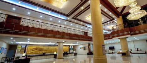 A spacious lobby with a high ceiling, multiple levels, and a reception desk.