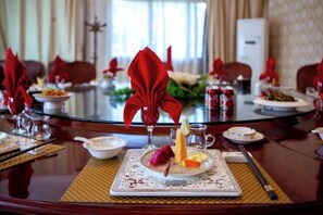 A dining table set with plates, glasses, and a red napkin. - Tianlongshan Hotel (Dexing)